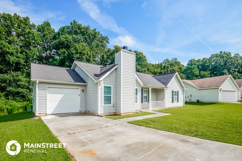 a white house with white siding and green grass and trees