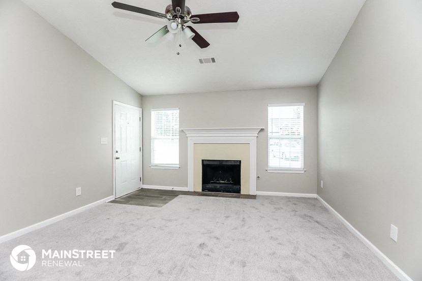 the living room with fireplace and ceiling fan