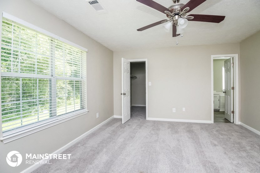 an empty living room with a ceiling fan and a large window