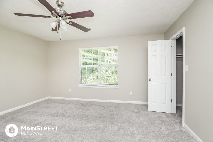 the master bedroom has a carpeted floor and a ceiling fan