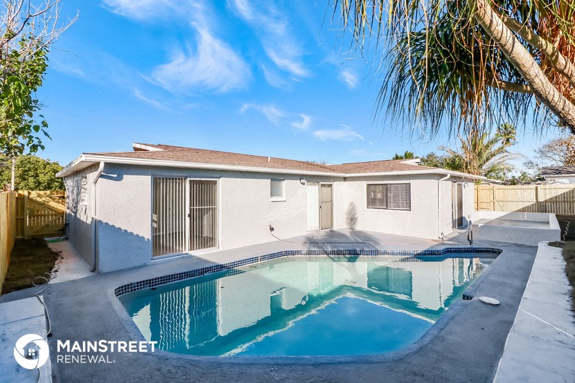 a house with a pool in front of it and a palm tree