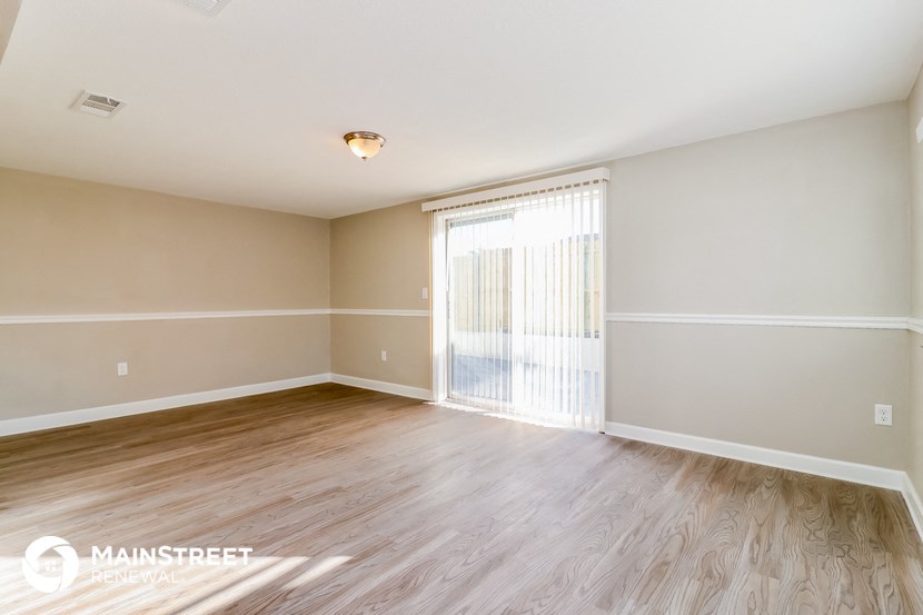 the spacious living room with wood flooring and sliding glass doors to the patio