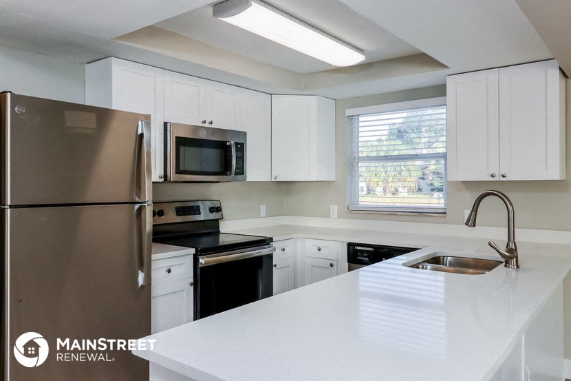 a white kitchen with stainless steel appliances and white counter tops