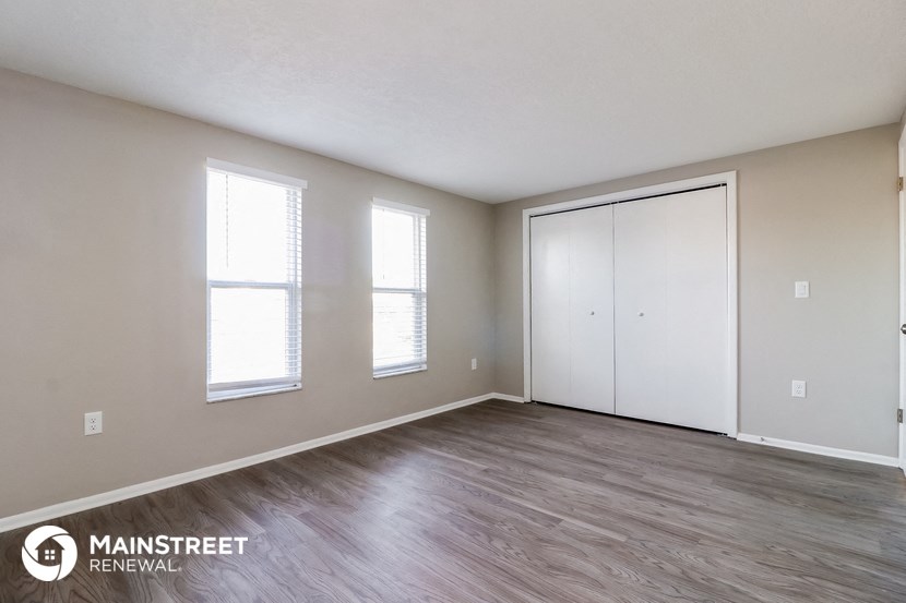 the spacious living room with white walls and wood flooring