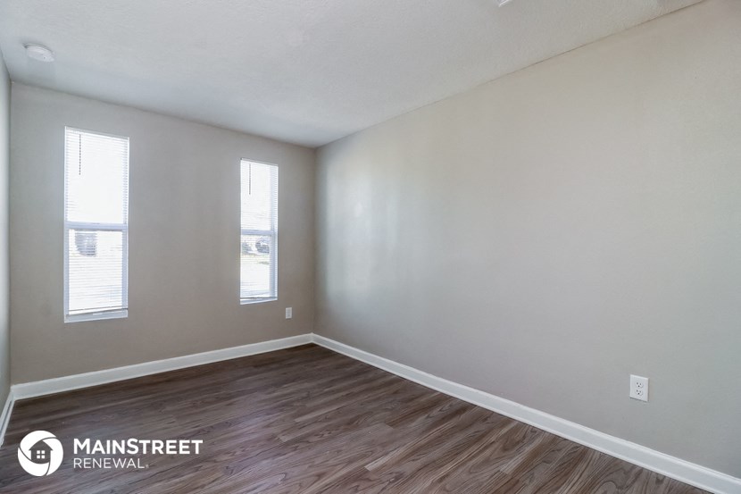 the spacious living room with wood flooring and white walls