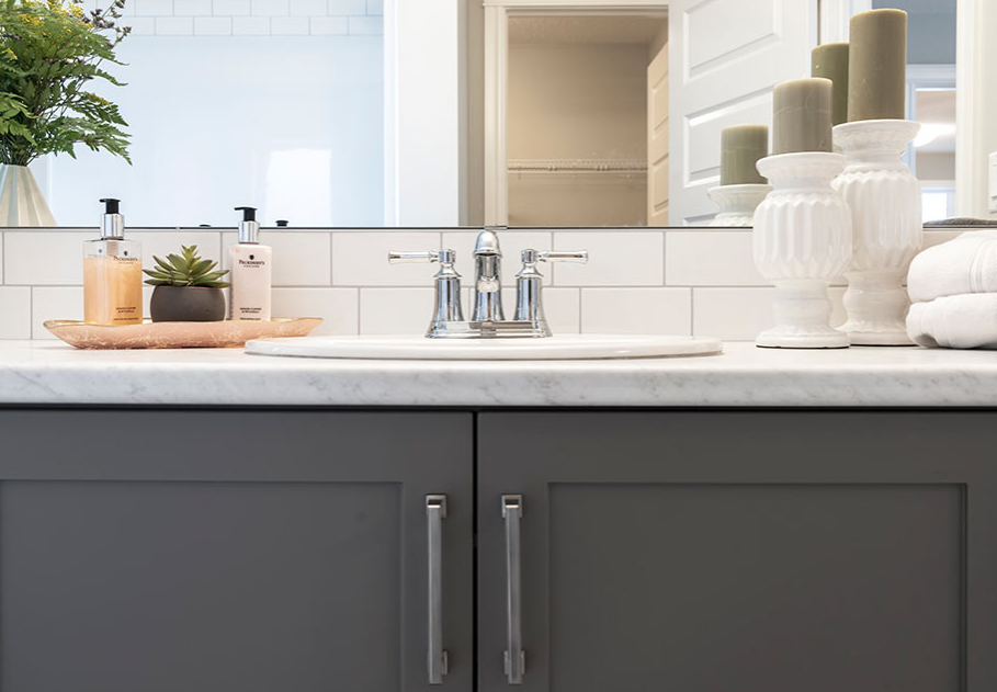 a bathroom with gray cabinets and a sink and a mirror