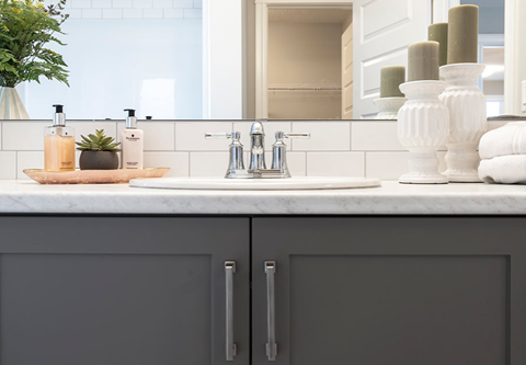 a bathroom with gray cabinets and a sink and a mirror