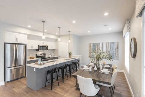 an open kitchen and dining area with stainless steel appliances and a wooden table