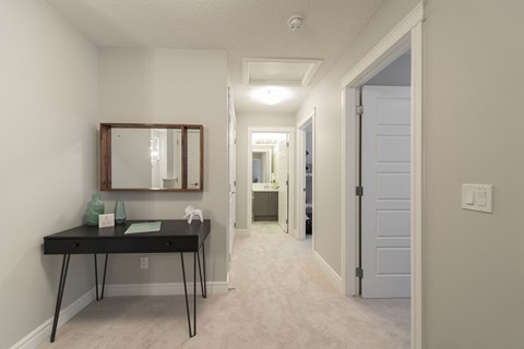a hallway with a desk and a mirror in a home