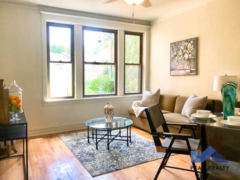 a living room with a couch and a table and three windows