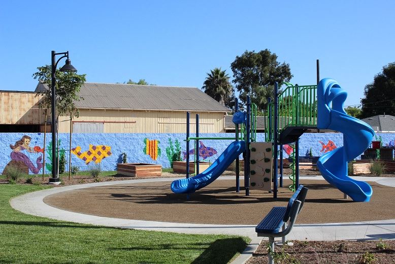 a playground with a blue slide and a bench