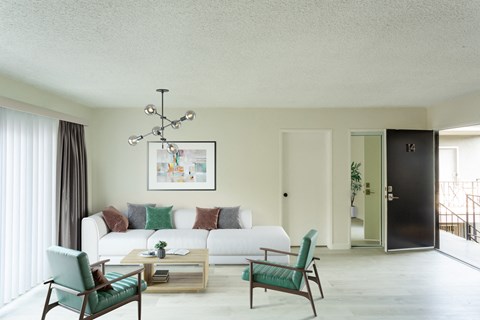 a living room with a white couch and green chairs