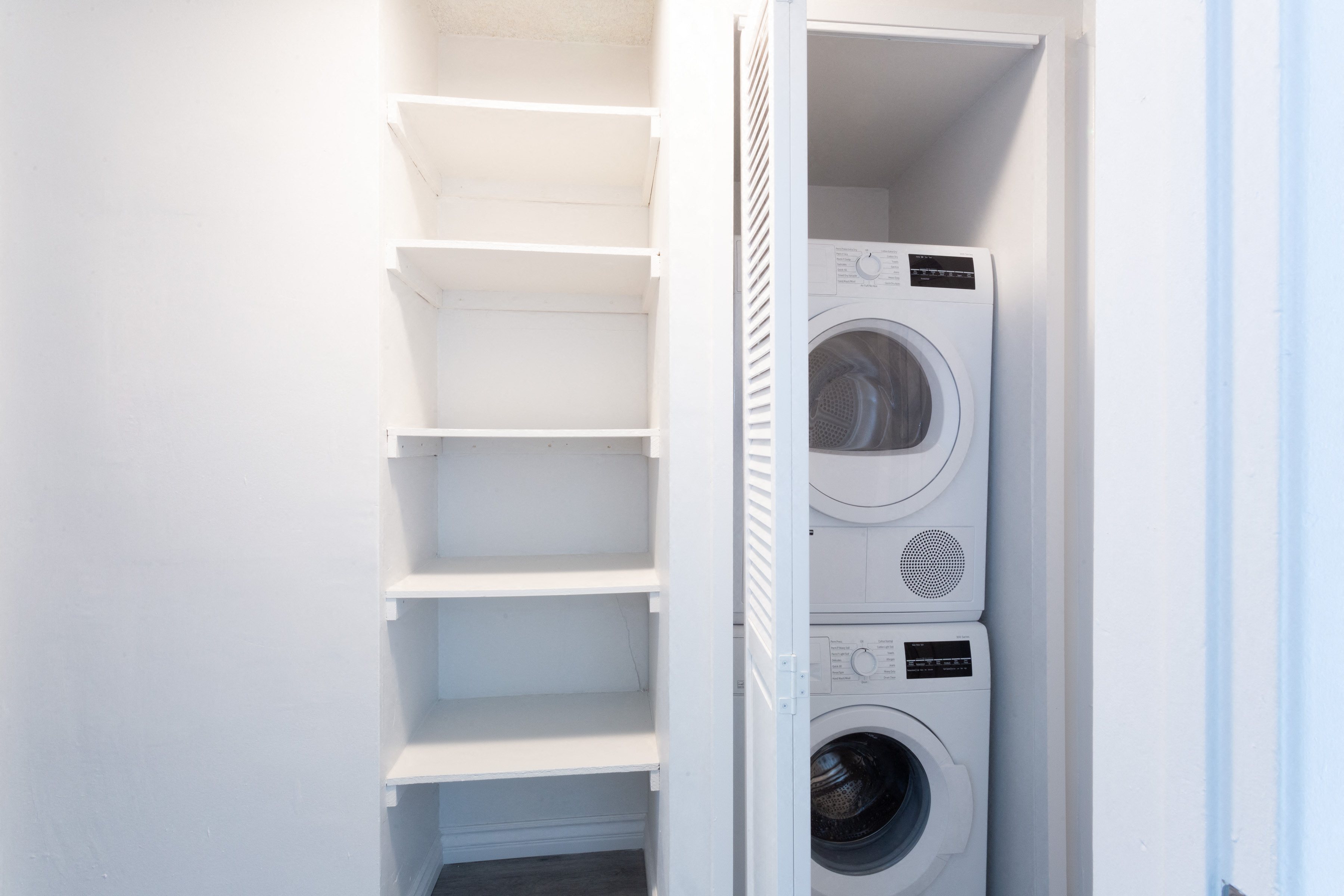 Washer and dryer next to stack of white shelves