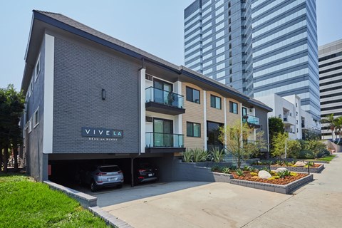 Exterior with cars in garage, plants out front, and balconies
