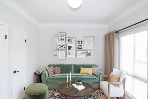 a living room with a green couch and a gallery of pictures on the wall