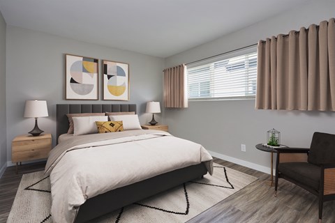Spacious bedroom with full sized bed, long window, wooden flooring and light grey walls