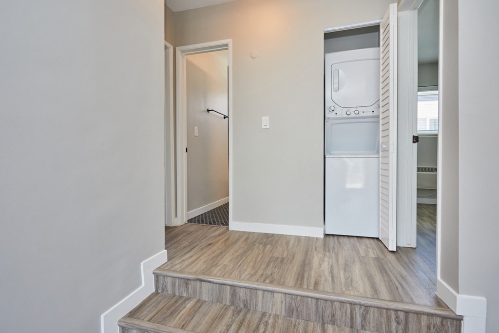 Hallway Hallway with light grey walls, wooden floors, and washer and dryer