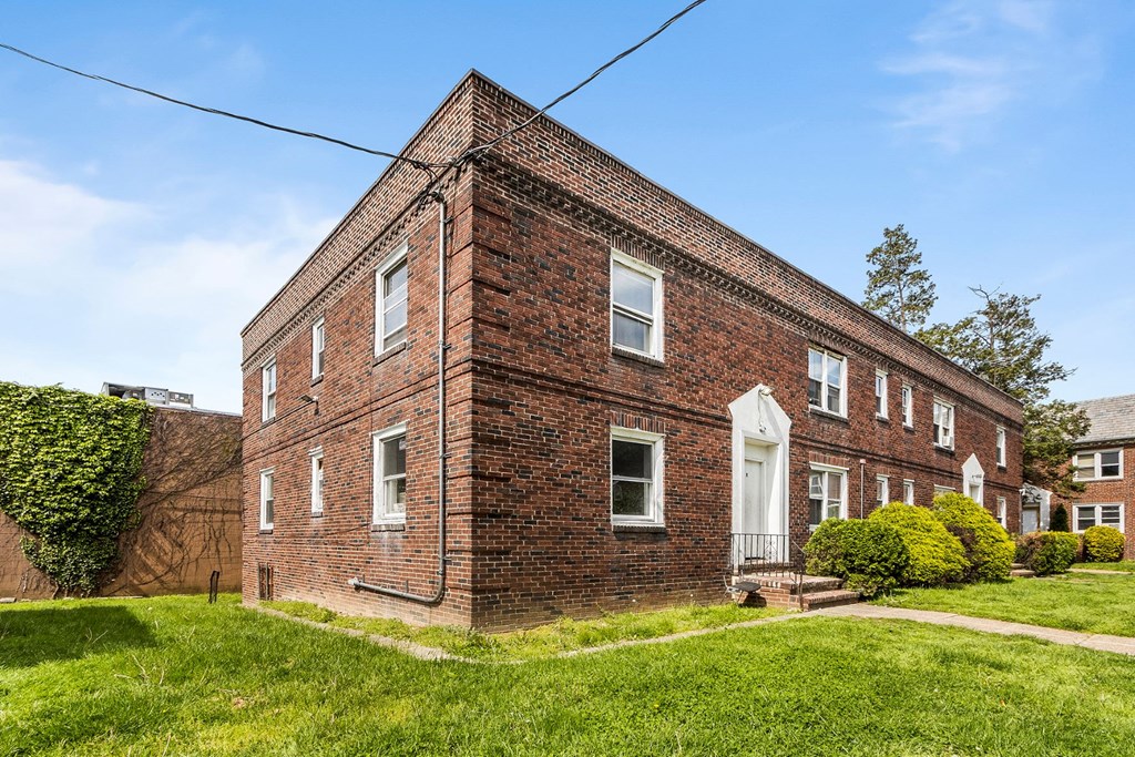 a red brick house with a white door and a green lawn