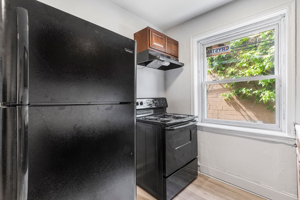 a kitchen with a stove and a refrigerator next to a window
