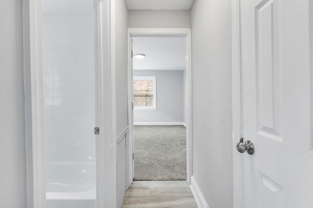 a bedroom with a white door and a hallway with a window