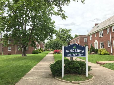 a sign for grand leeper park in front of a brick building