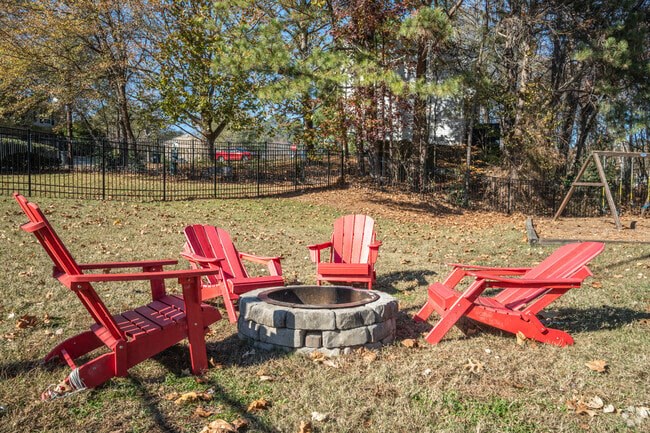 Two red chairs and a table are in a yard.