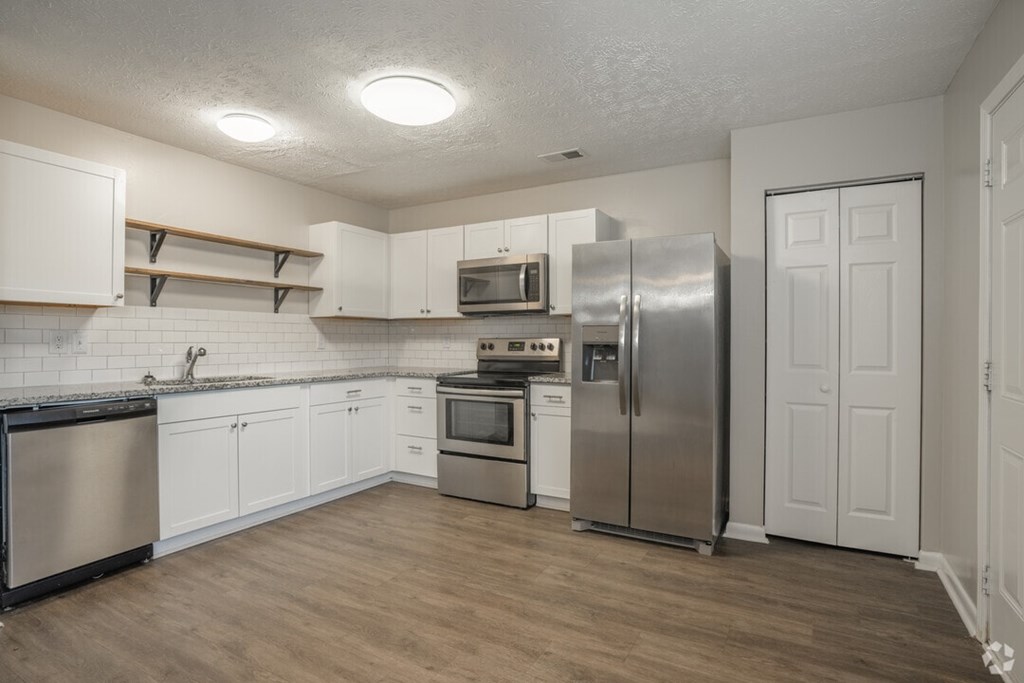 A kitchen with white cabinets and a stainless steel refrigerator.