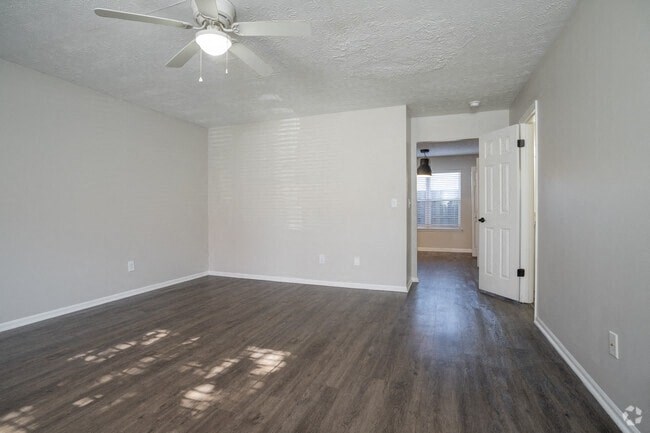 A room with a ceiling fan and wooden flooring.
