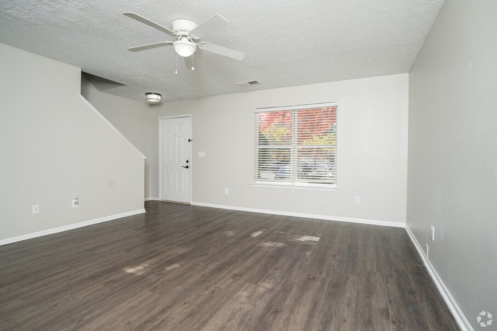 A room with a ceiling fan and a window with blinds.