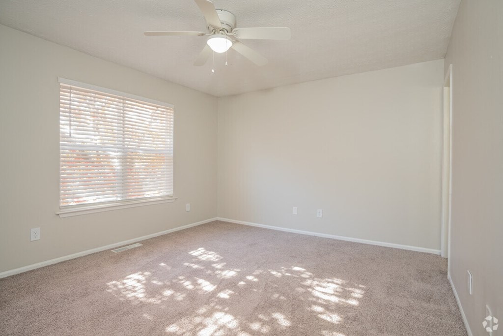 A room with a ceiling fan and a window with blinds.