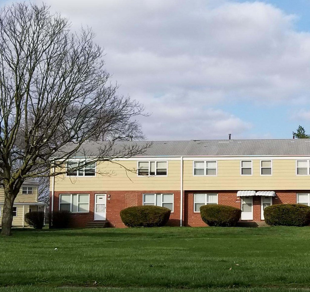 an apartment building on the side of a green field