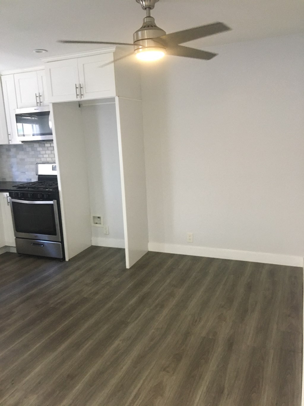 an empty living room with wooden floors and a ceiling fan