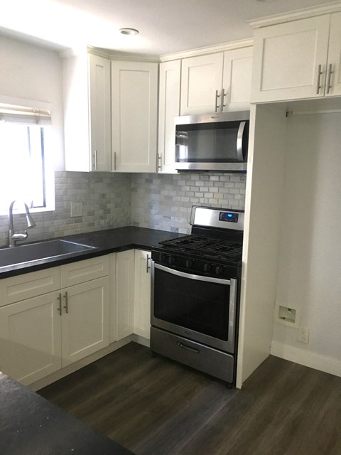 a kitchen with white cabinets and a stove and a microwave