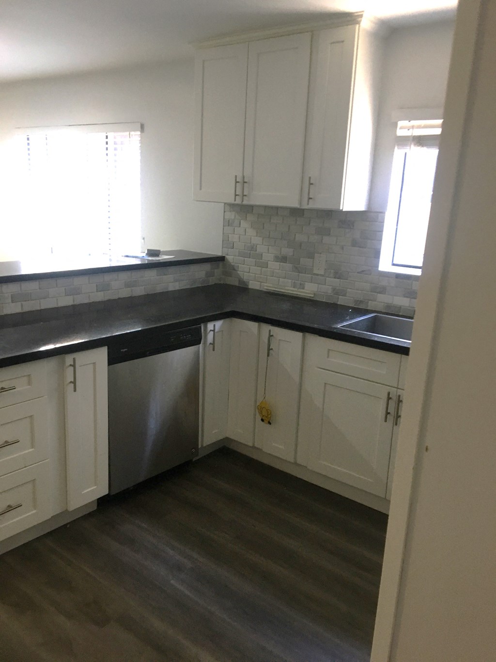 an empty kitchen with white cabinets and black counter tops