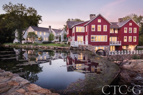 A red house is reflected in the water in front of it.