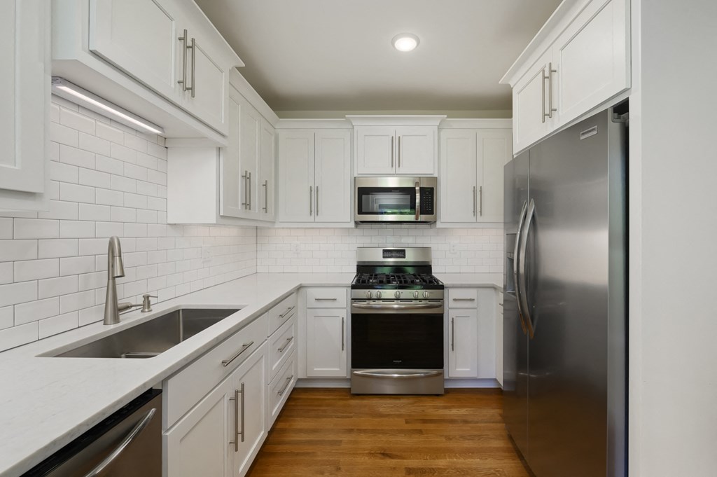 an empty kitchen with white cabinets and stainless steel appliances