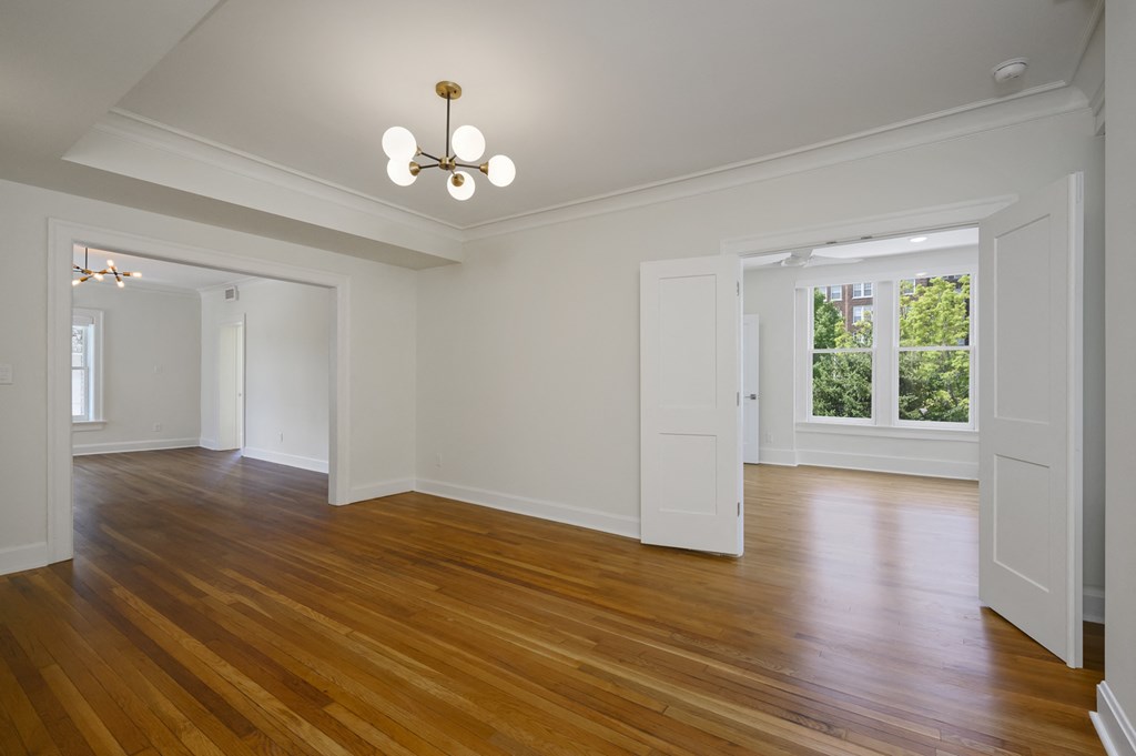 a living room with white walls and wood floors and a chandelier