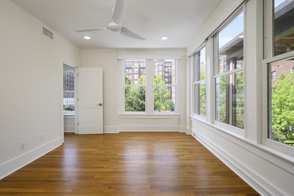 an empty living room with large windows and wood floors