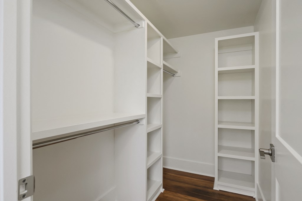 a walk in closet with white shelves and a white door