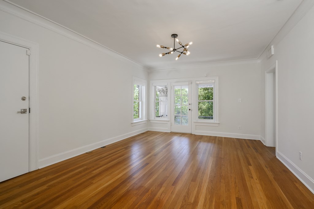 a living room with white walls and wood floors and a chandelier