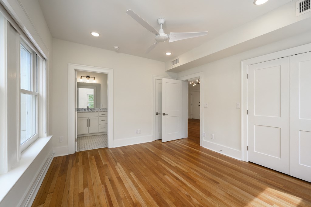 a living room with white walls and wooden floors and a ceiling fan