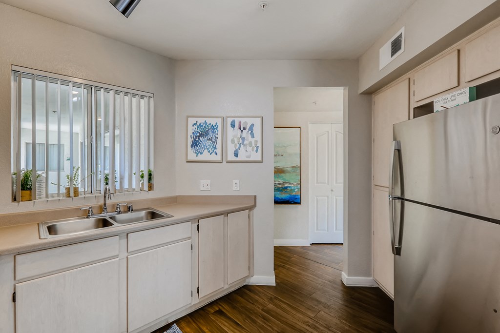 an open kitchen with white cabinets and a stainless steel refrigerator