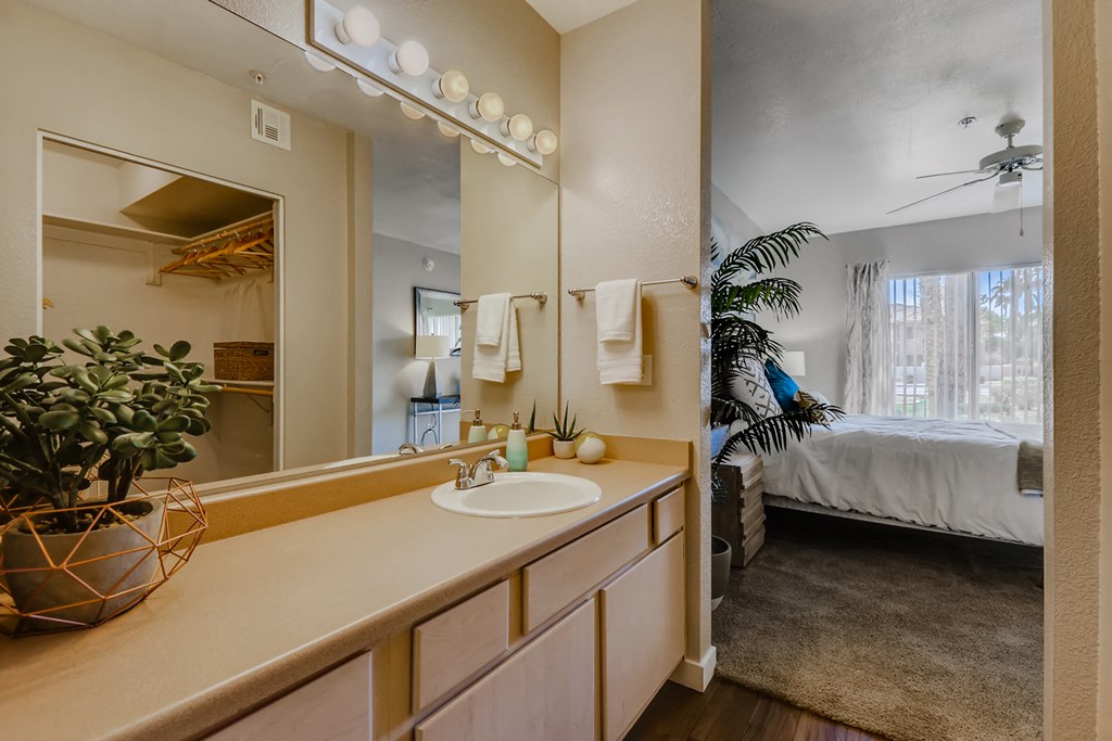 a bathroom with a sink and a mirror and a bedroom with a bed