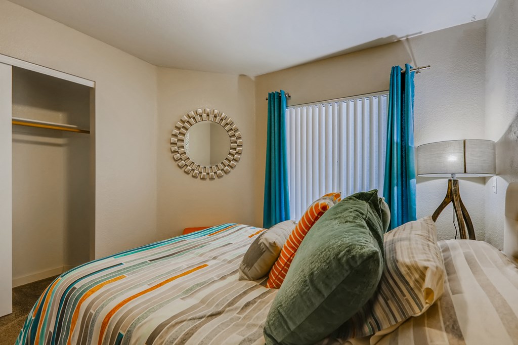 a bedroom with a bed with pillows and curtains and a window