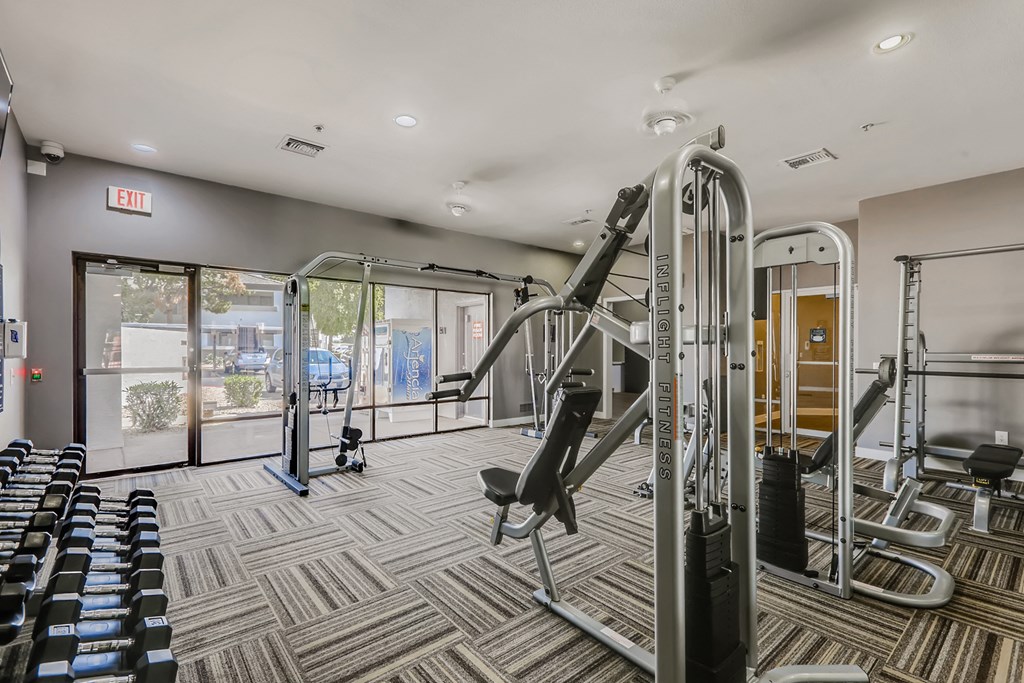 a gym with cardio machines and weights in a building with glass doors