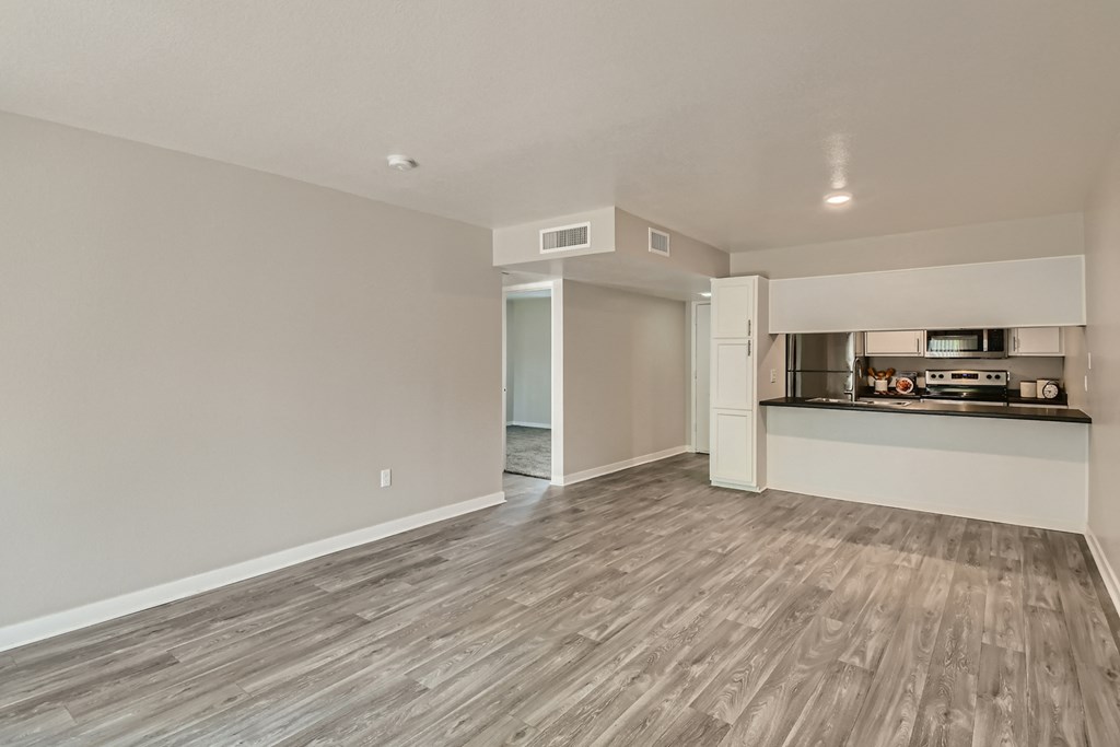 an empty living room and kitchen with wood flooring