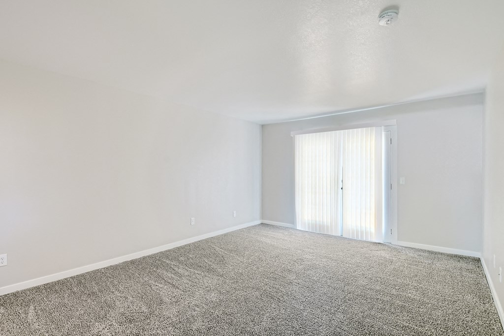 an empty living room with white walls and a window