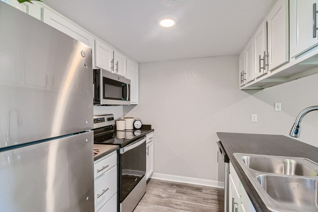 an empty kitchen with stainless steel appliances and white cabinets