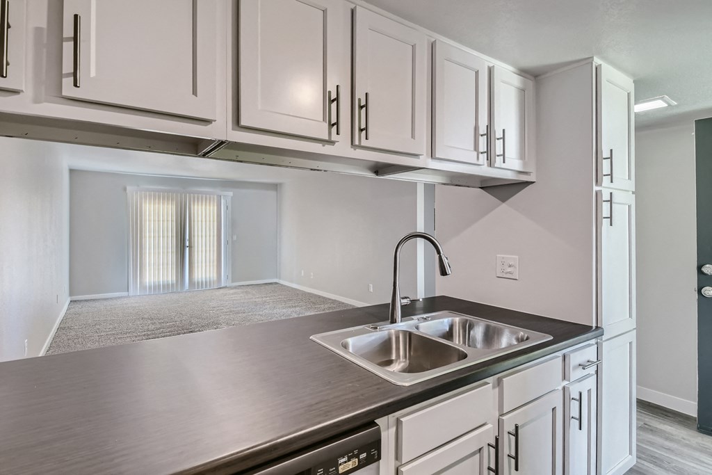 an empty kitchen with white cabinets and a sink