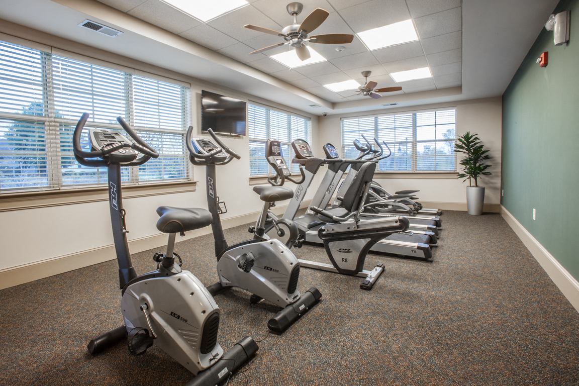 a gym with cardio machines and a large window